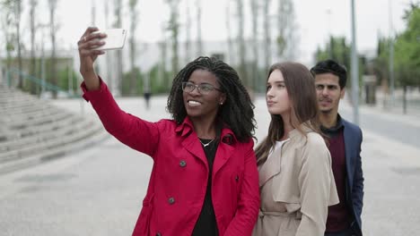Two-women-and-man-making-selfie-outside,-posing,-smiling